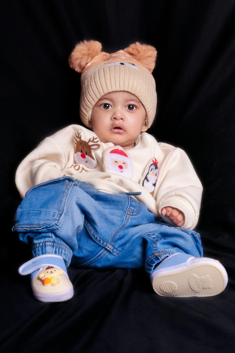 Baby wearing a cute hat and sweater with christmas-themed sweater.